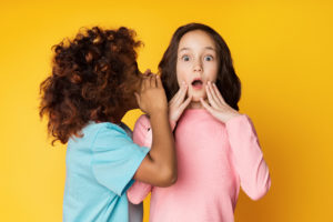 Girl telling secret to her friend, whispering in ear